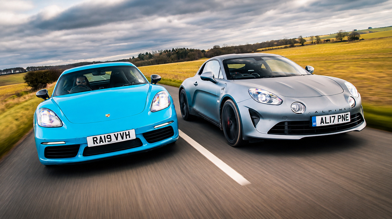 Blue Porsche and silver Alpine sports cars driving side by side on a country road under a cloudy sky.