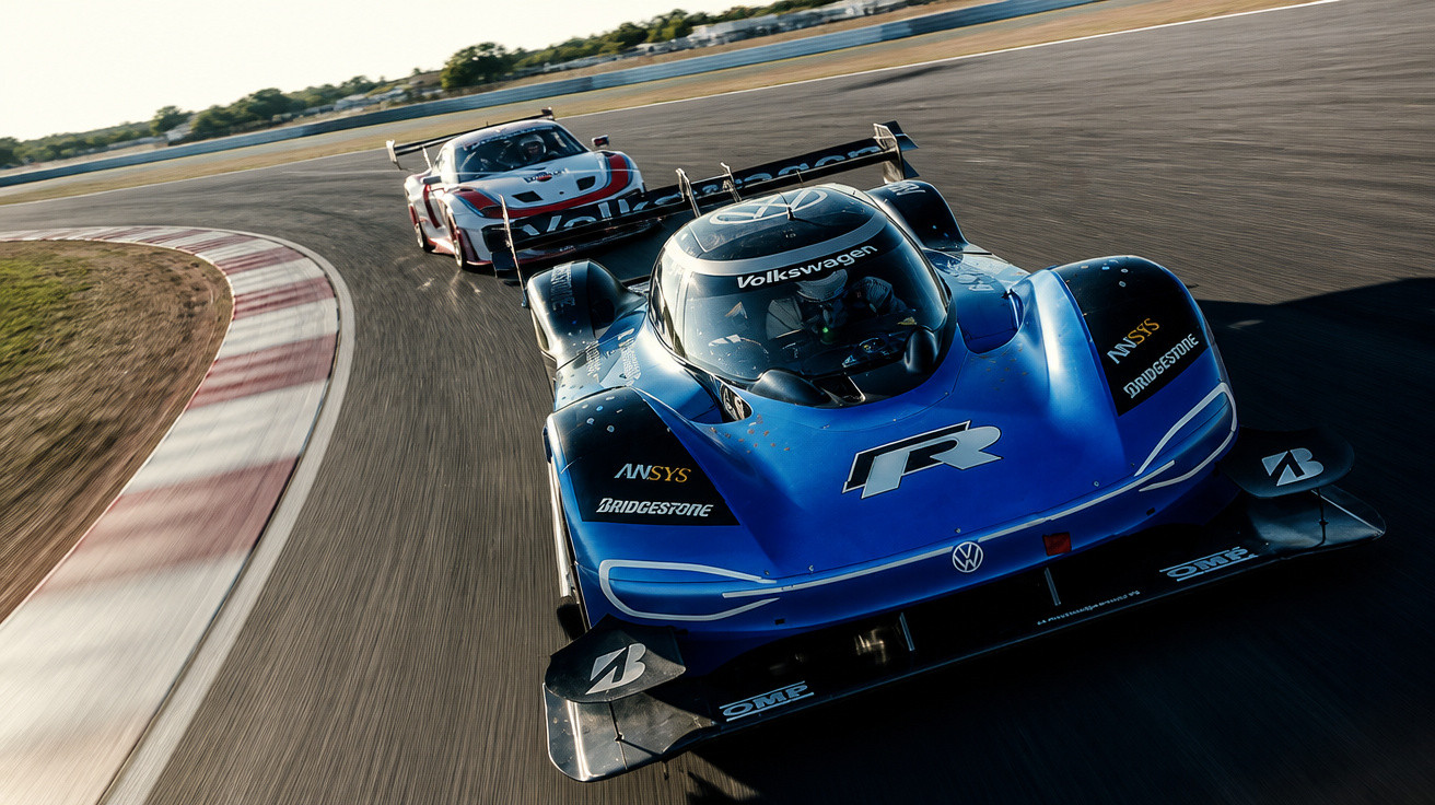 Blue Volkswagen electric race car leading a white and red race car on a curved racetrack in daylight.