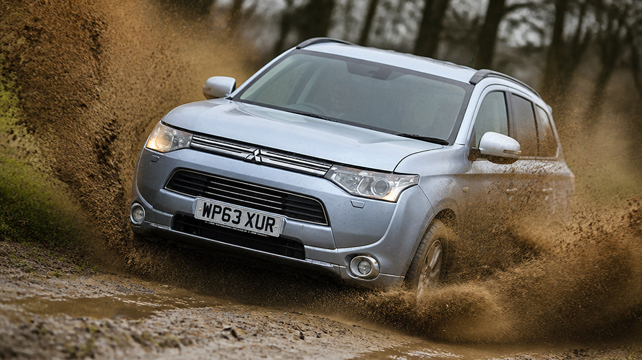Silver Mitsubishi SUV splashing mud while driving off-road through a forest trail.